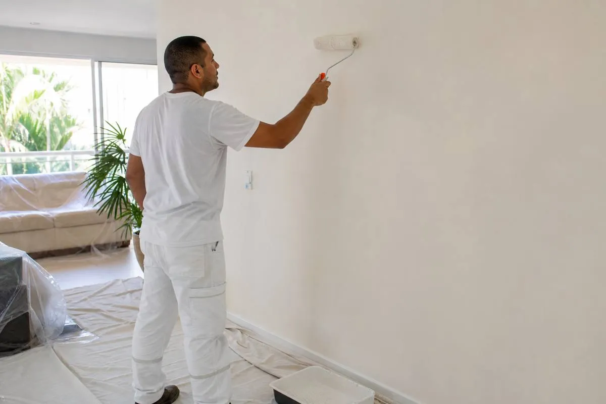 Pintor profissional pintando parede interna de sala com rolo em Tapera da Base
