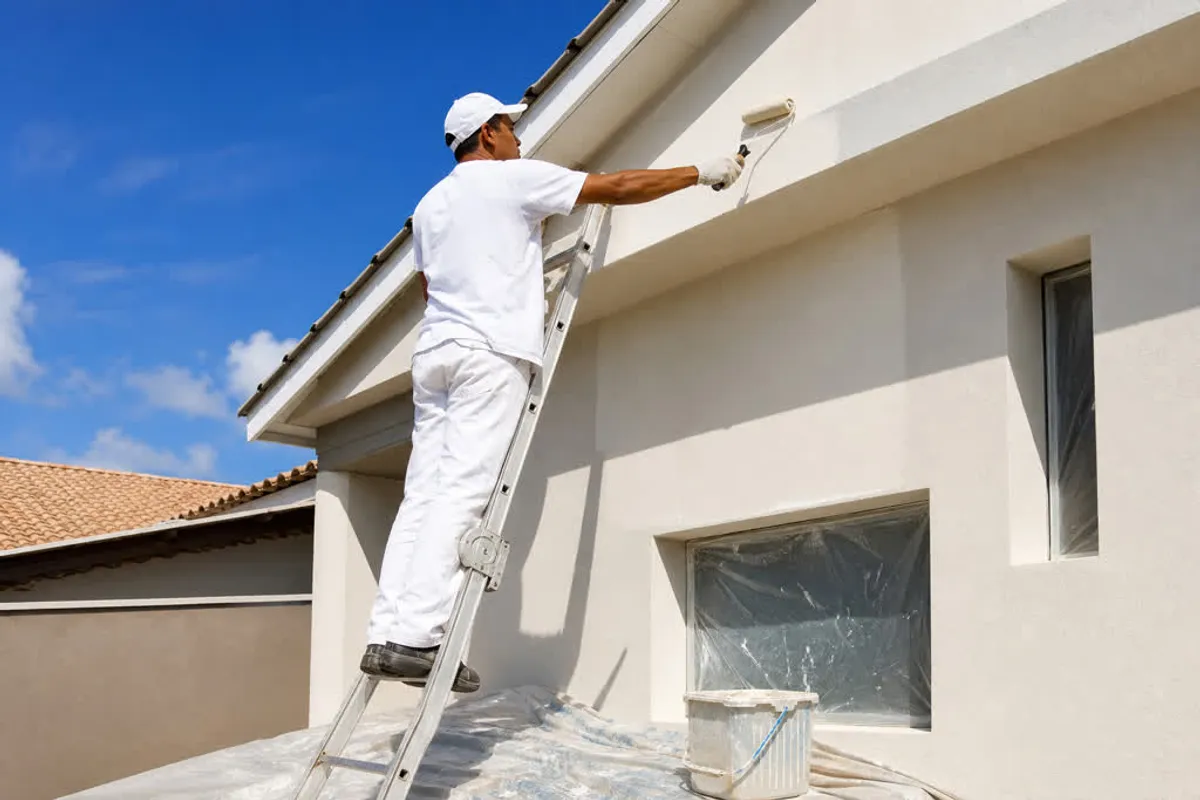 Pintor profissional pintando a fachada de uma residência na Freguesia do Ribeirão da Ilha